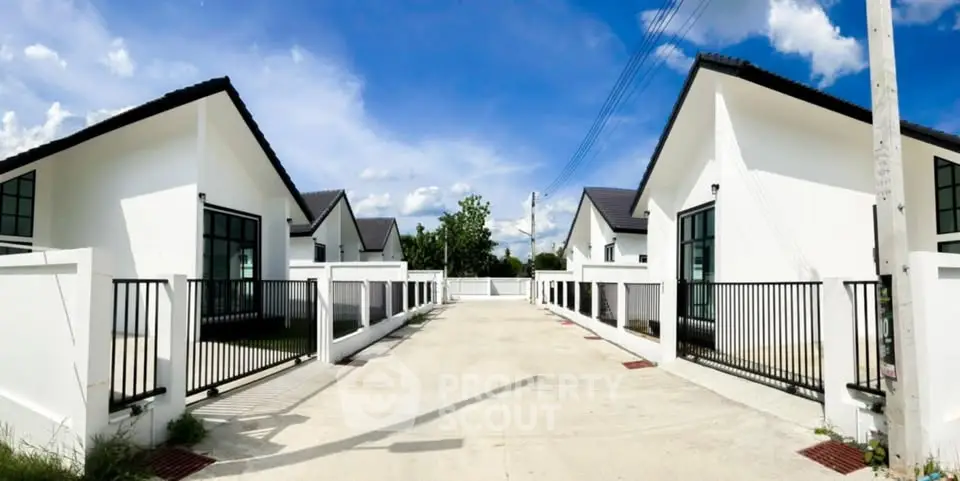 Modern white houses with sleek design and spacious driveways under a clear blue sky.