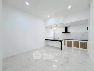 Modern minimalist kitchen with sleek black countertops and white cabinetry in a spacious open layout.