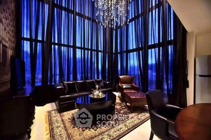 Luxurious living room with high ceilings, elegant chandelier, and floor-to-ceiling windows.