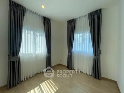Bright and airy unfurnished room with large windows draped in elegant curtains, ready for personalization in a modern home.