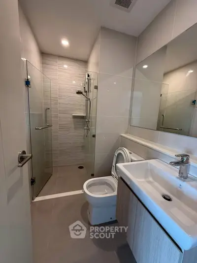 Modern bathroom with glass shower and sleek fixtures in contemporary apartment.