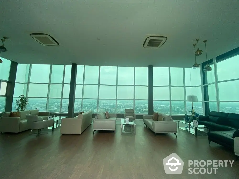 Expansive high-rise living room with floor-to-ceiling windows offering panoramic city views, modern furnishings, and ample natural light.