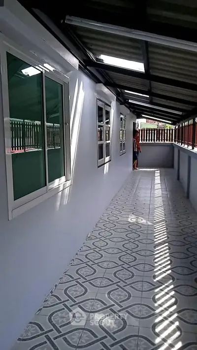 Spacious corridor with tiled flooring and large windows in a modern building.