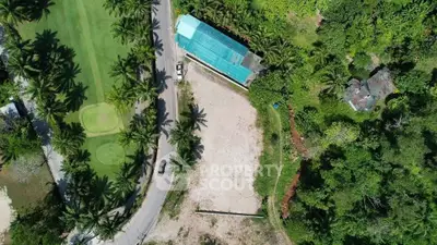 Aerial view of lush green landscape with a building and road, ideal for real estate development.