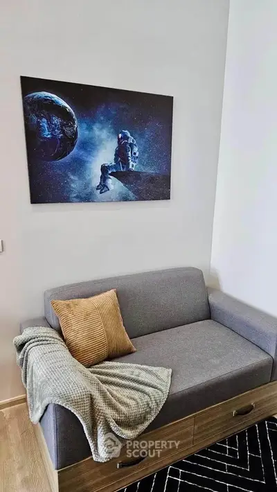 Modern living room with stylish gray sofa and space-themed wall art, perfect for cozy relaxation.