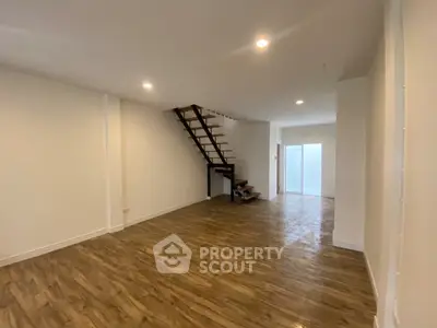 Spacious open-plan living area with wooden flooring and modern staircase, perfect for contemporary living.