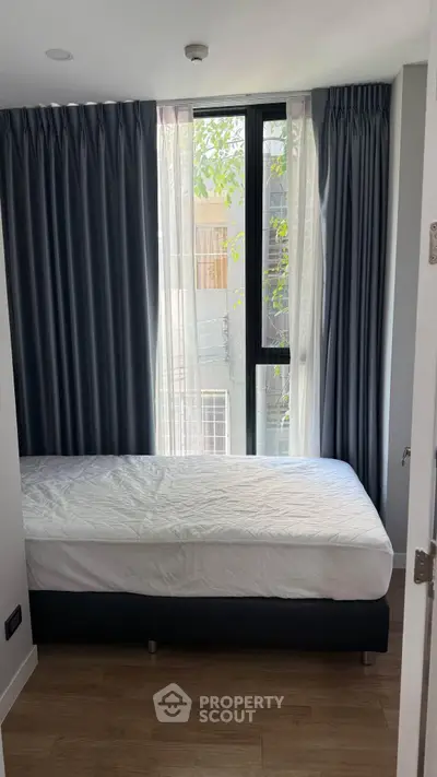 Cozy bedroom with large window and elegant curtains in modern apartment