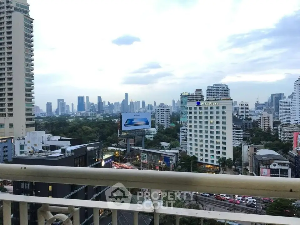Stunning cityscape view from a high-rise balcony overlooking urban skyline and lush greenery.