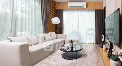 Elegant living room with modern decor and large windows, featuring a cozy sofa and stylish coffee table.
