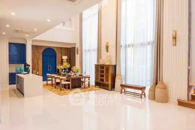 Luxurious open-plan living room with elegant dining area and high ceilings, featuring modern decor and ample natural light.