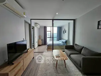 Modern living room with sliding glass doors leading to a cozy bedroom, featuring stylish furniture and natural light.