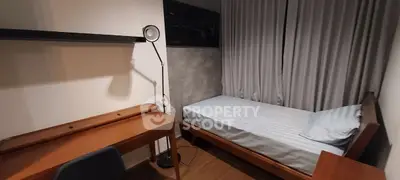 Cozy bedroom with single bed, desk, and floor lamp, ideal for a minimalist lifestyle.