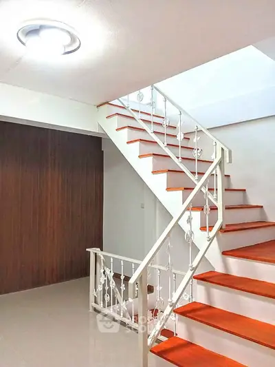 Modern staircase with wooden steps and white railing in a bright interior space