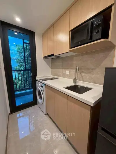 Modern kitchen with sleek cabinetry, built-in appliances, and a washing machine, offering functionality and style.