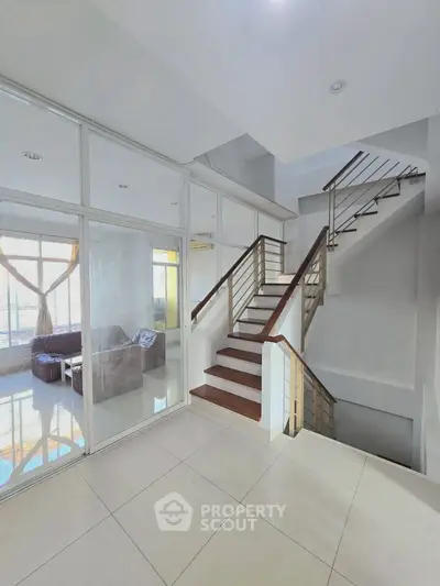 Spacious modern interior with elegant staircase and glass-walled living area, perfect for contemporary living.