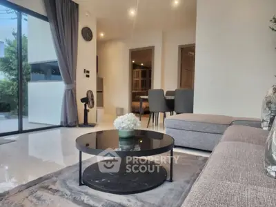 Modern living room with sleek furniture and large windows offering natural light.