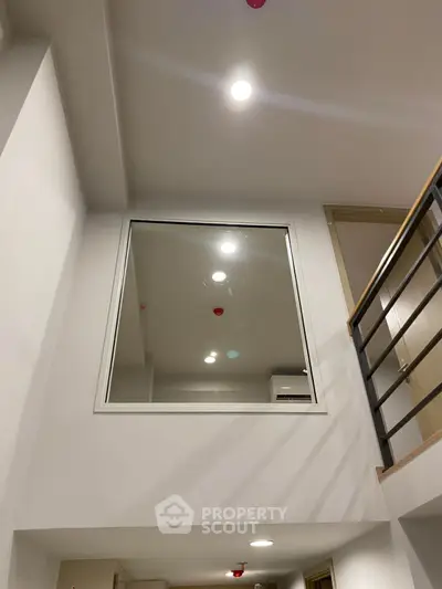 Modern interior with high ceiling and large window, showcasing sleek design and ample lighting.