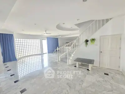 Spacious modern living room with marble flooring and elegant staircase