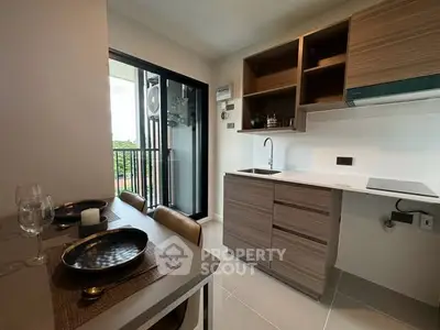 Modern kitchen with open layout and balcony view, featuring sleek cabinetry and dining area.