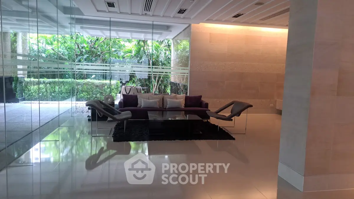 Luxurious modern living room with glass walls and garden view, featuring elegant furniture and stylish decor.