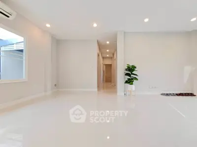 Spacious modern living room with glossy white tiles and natural light