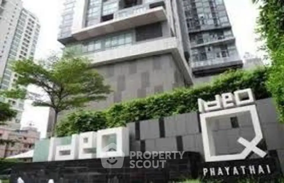 Modern high-rise building exterior with lush greenery and stylish signage.