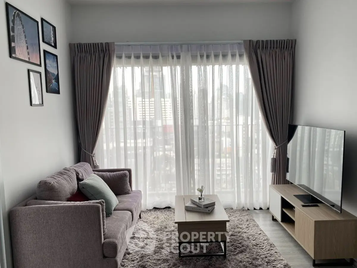 Modern living room with large window, cozy sofa, and flat-screen TV, perfect for relaxation.
