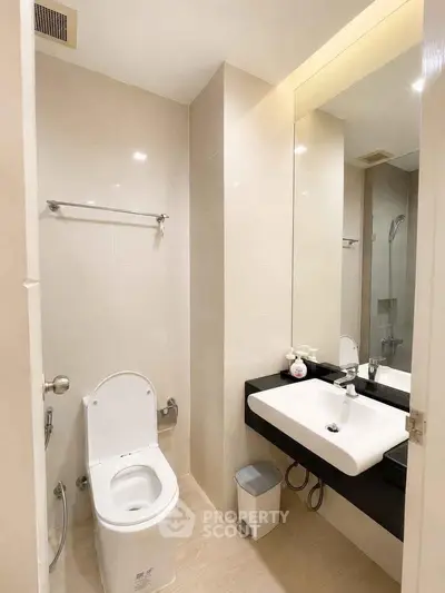 Modern bathroom with sleek fixtures and large mirror in a contemporary apartment.
