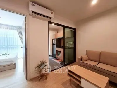 Modern apartment living room with open kitchen and cozy bedroom view.