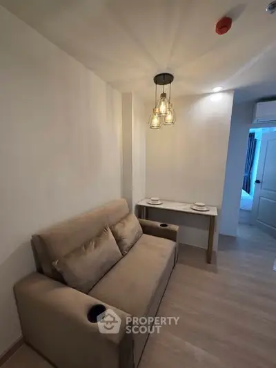 Cozy living room with modern sofa and stylish lighting in a compact apartment.