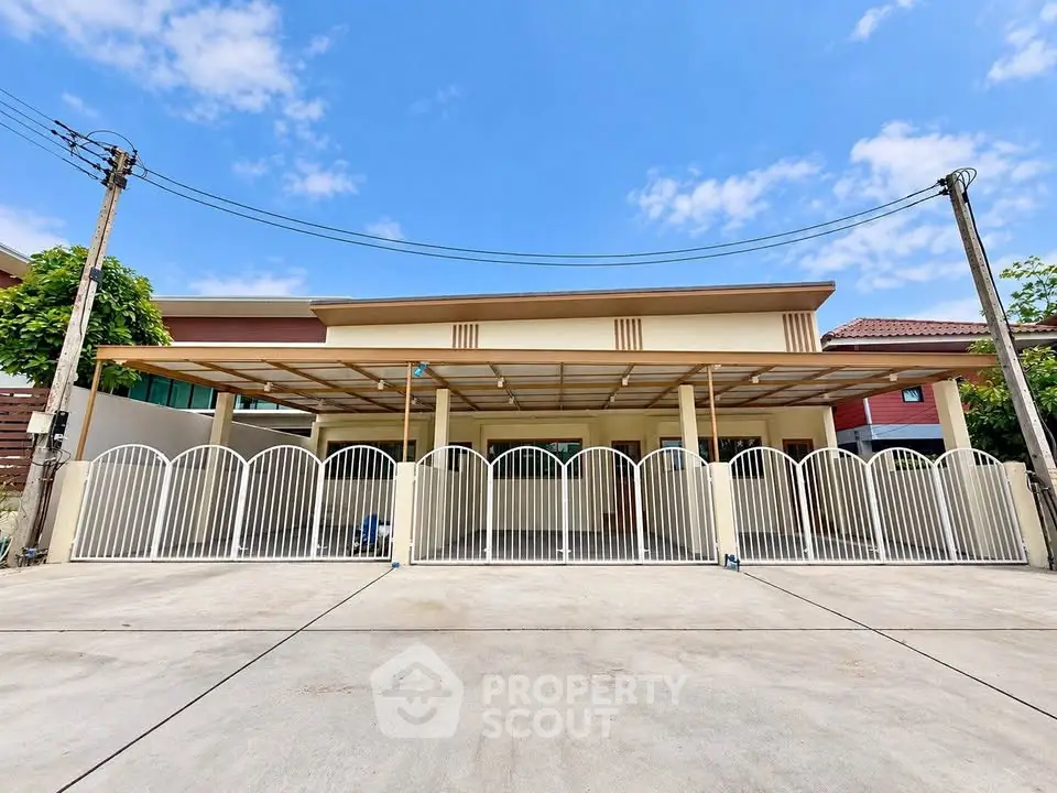 Modern single-story house with spacious driveway and gated entrance under clear blue sky.