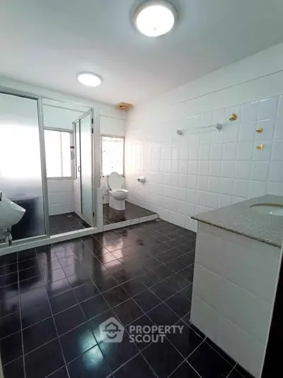 Spacious modern bathroom with sleek black tiles and large shower area.