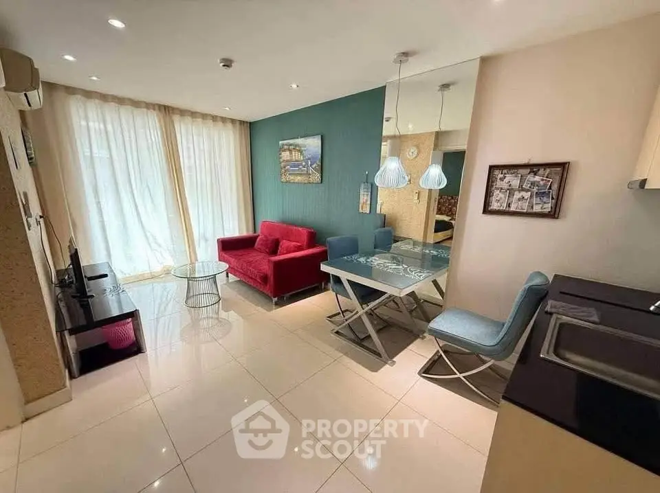 Modern living room with vibrant red sofa, glass table, and stylish decor in a cozy apartment setting.