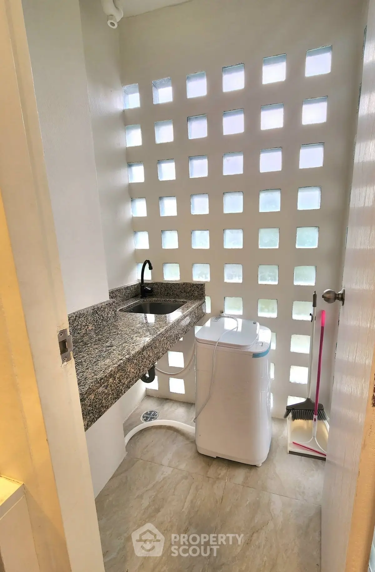 Compact laundry area with modern washing machine and granite countertop in bright space.