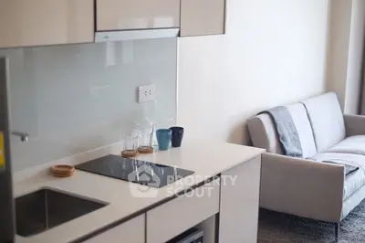 Modern kitchen with sleek design and cozy living area in open layout apartment.