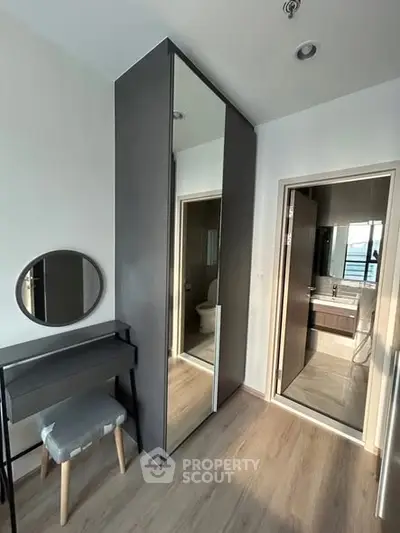 Modern bedroom with sleek wardrobe and ensuite bathroom, featuring stylish furniture and elegant design.