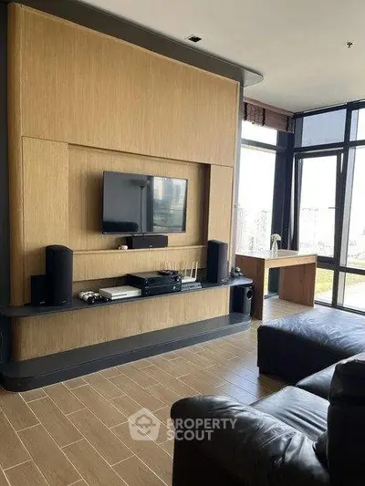 Modern living room with sleek entertainment center and large windows offering city views.