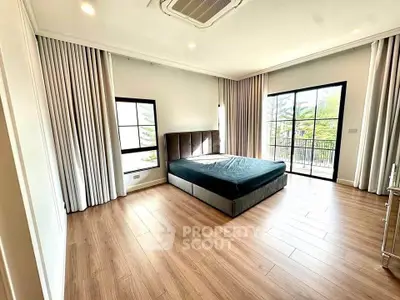 Spacious bedroom with large windows and balcony access in modern apartment.