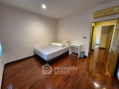 Spacious bedroom with wooden flooring and modern air conditioning unit