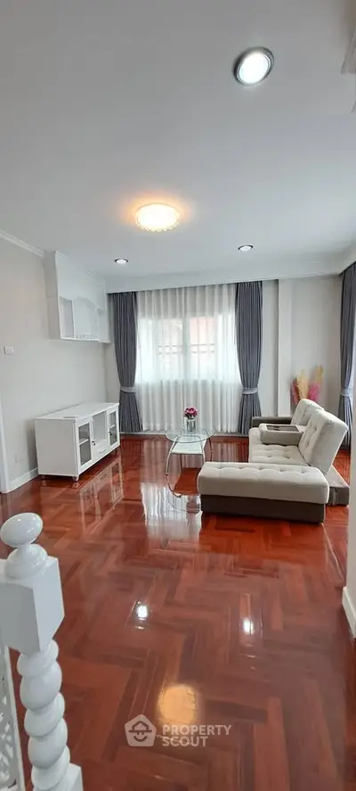 Spacious living room with elegant hardwood floors and modern furniture, perfect for relaxation and entertainment.