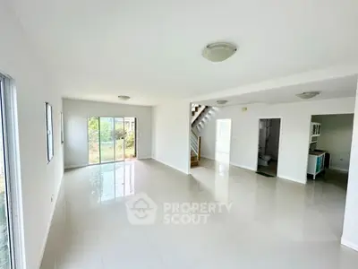 Spacious open-plan living room with glossy tile flooring and abundant natural light.