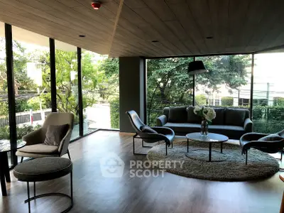Modern living room with large windows and stylish furniture, offering a serene garden view.