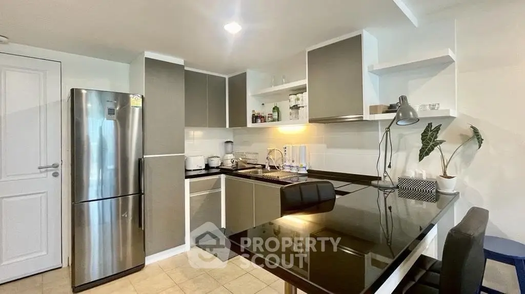 Modern kitchen with sleek cabinetry and stainless steel fridge in a stylish apartment.