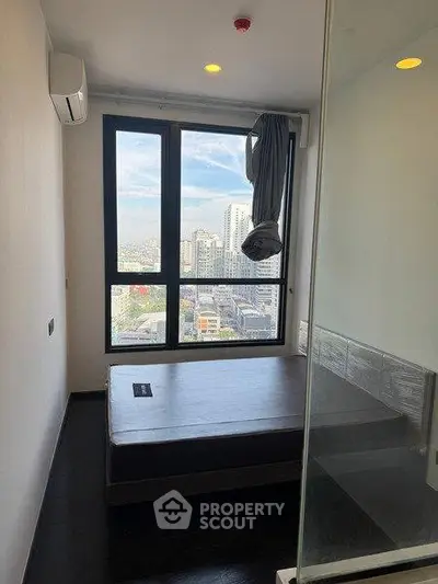 Modern bedroom with city view, large window, and minimalist design in high-rise apartment.