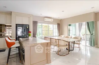 Spacious modern kitchen with open layout and elegant dining area, featuring marble countertops and stylish decor.