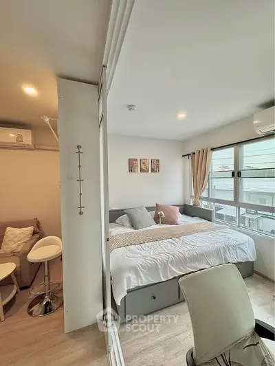 Cozy bedroom with large windows and modern decor in a stylish apartment.