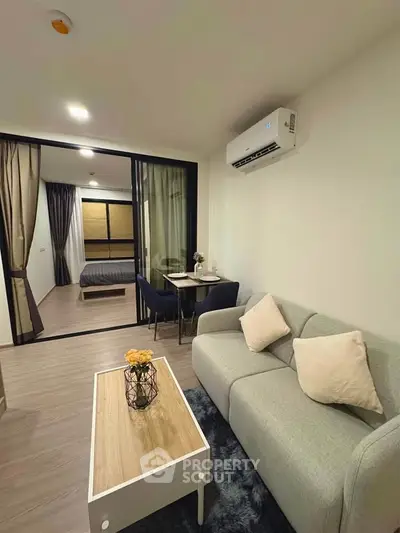 Modern living room with cozy sofa and view into stylish bedroom