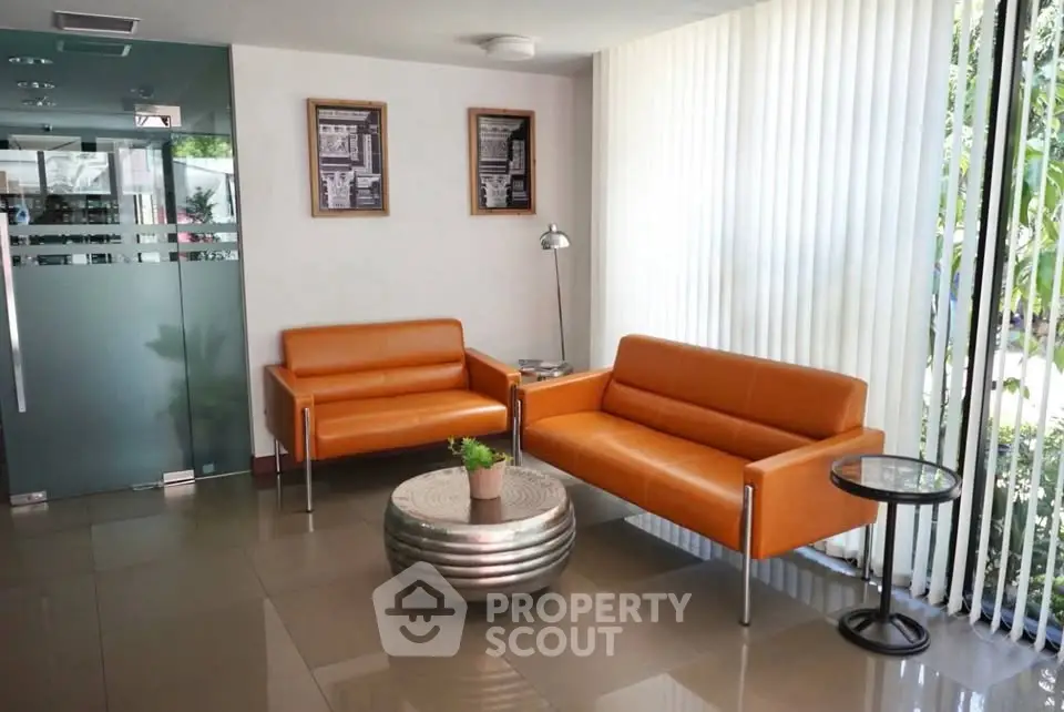 Modern lobby with orange sofas and glass door, perfect for welcoming guests.