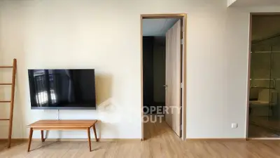 Modern living room with wall-mounted TV and wooden flooring, showcasing minimalist design.