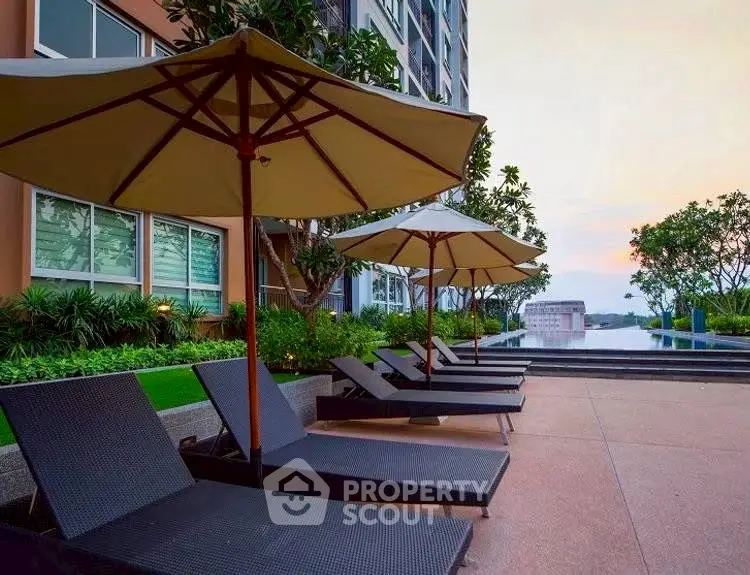 Luxurious poolside area with sun loungers and umbrellas at a modern residential building.